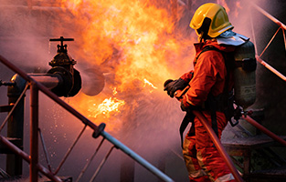 Firefighter fighting fire from oil pipeline leak and explosion on oil rig